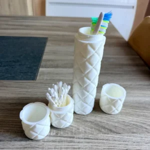 Set de voyage matelassé blanc comprenant une boîte brosse à dents voyage et un étui coton-tige ouverts sur une table