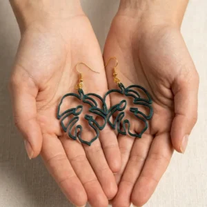 Paire de boucles d'oreilles Monstera 3DWorlds présentées au creux des mains
