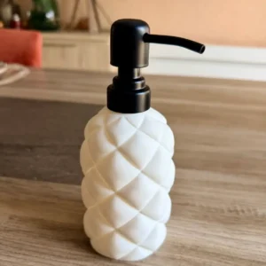 Distributeur de savon liquide élancé blanc mat, modèle Slim Ovale au motif matelassé puffy avec pompe noire.