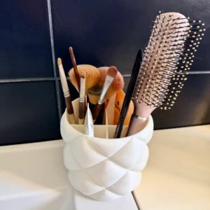 Organisateur salle de bain blanc matelassé avec pinceaux de maquillage et brosse à cheveux posé sur un lavabo