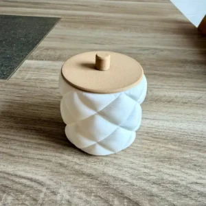 Pot à cotons design effet matelassé blanc mat avec son couvercle amovible couleur bois doté d'une petite poignée.