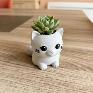 Pot en forme de chat mignon de la collection 'Verdanelle', couleur blanc mat, imprimé en 3D avec visage peint, tenant une succulente sur une table en bois.