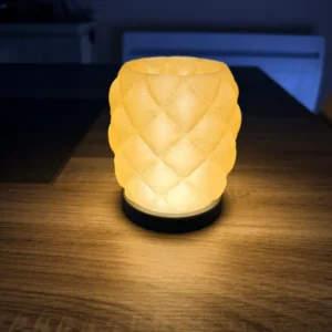 Lampe d'ambiance design Puff Aura avec un corps jaune translucide au motif capitonné et une base noire pailletée allumée