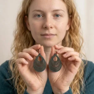Paire de boucles d'oreilles pendantes noir ajourées tenues dans les mains