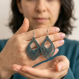 Paire de boucles d'oreilles pendantes vert ajourées tenues dans les mains