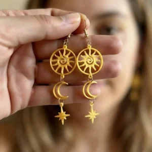 Détail des boucles d'oreilles articulées soleil lune étoile or brillant tenues en main