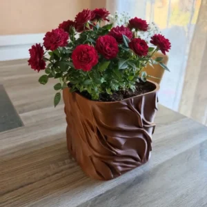 Cache-pot design organique Moka en impression 3D rempli de fleurs rouges sur une table