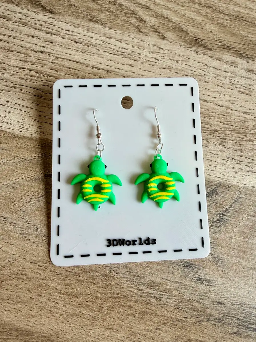 Boucles d'oreilles tortue donuts présentées sur un support siglé 3DWorlds.